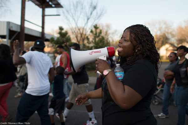 A Black woman speaking into a bullhorn at a protest
