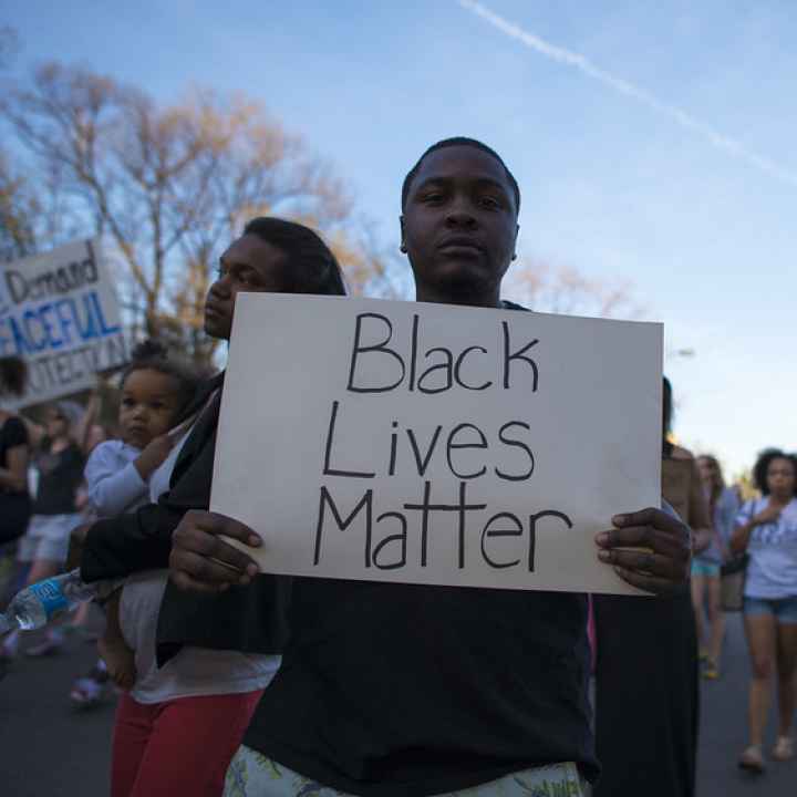 Young African American man holding a sign that reads Black Lives Matter 